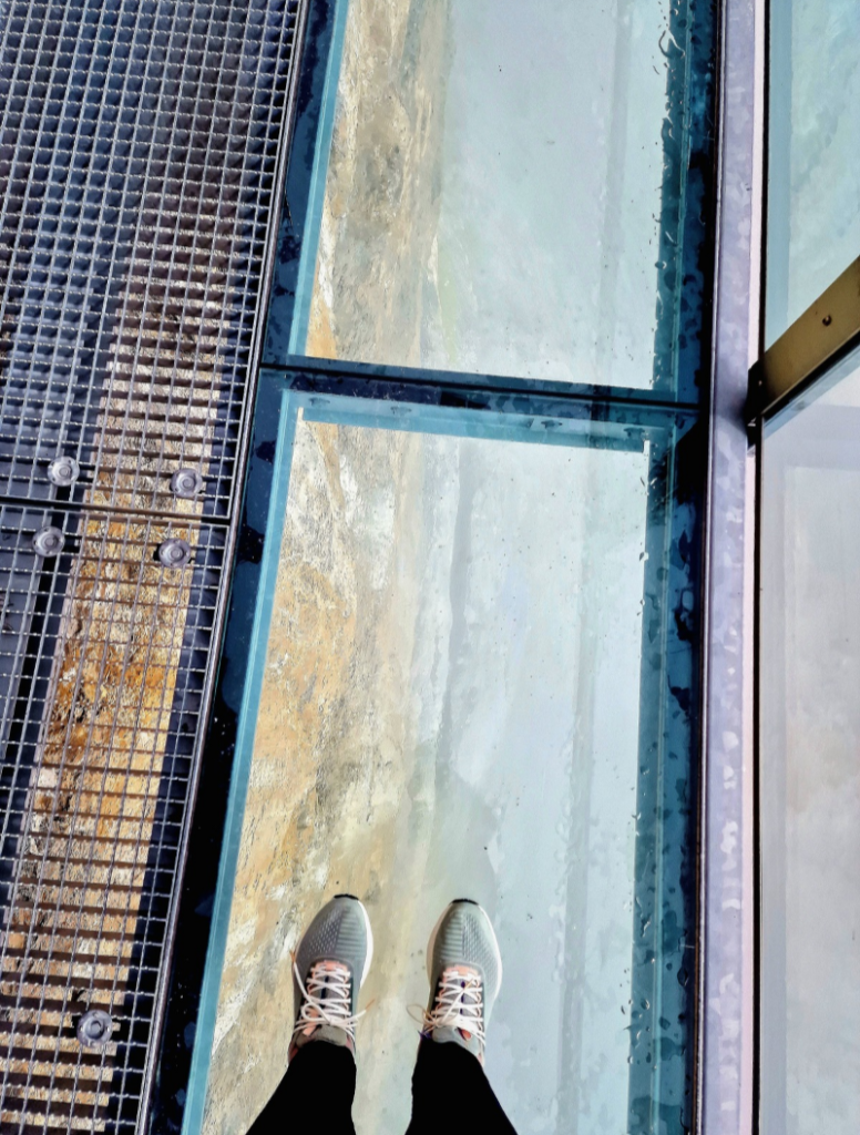 My feet standing on the glass walkway on the way to The Thrill Walk. The glass hangs over the mountainside, or you can walk on a grated pathway instead.