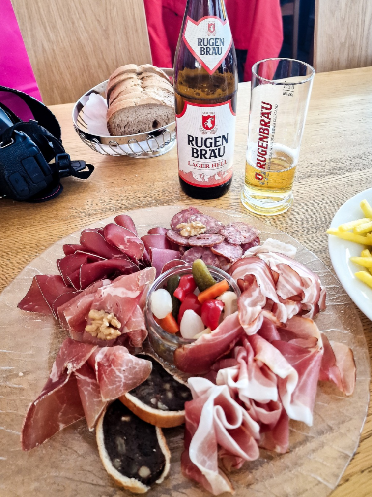 A meal from the 360° Restaurant Piz Gloria. A plate of European cold meats, a basket of bread and a bottle and glass of local beer (Rugen Brau).
